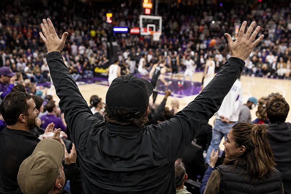 Fan with hands raised courtside at a basketball game
